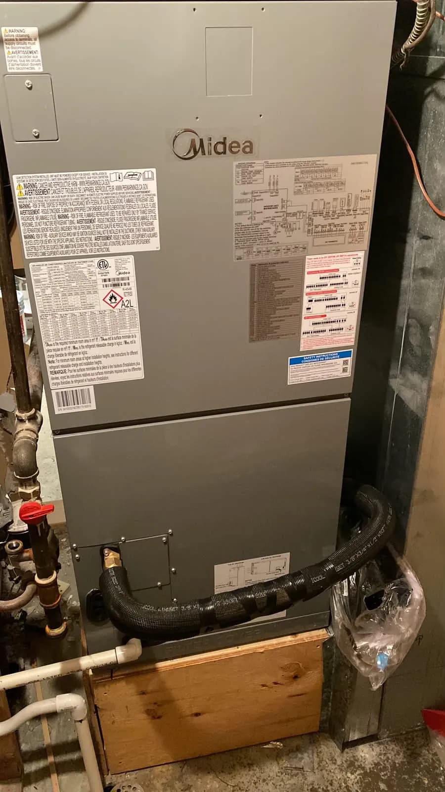 Midea air handler on a raised base in a basement mechanical room