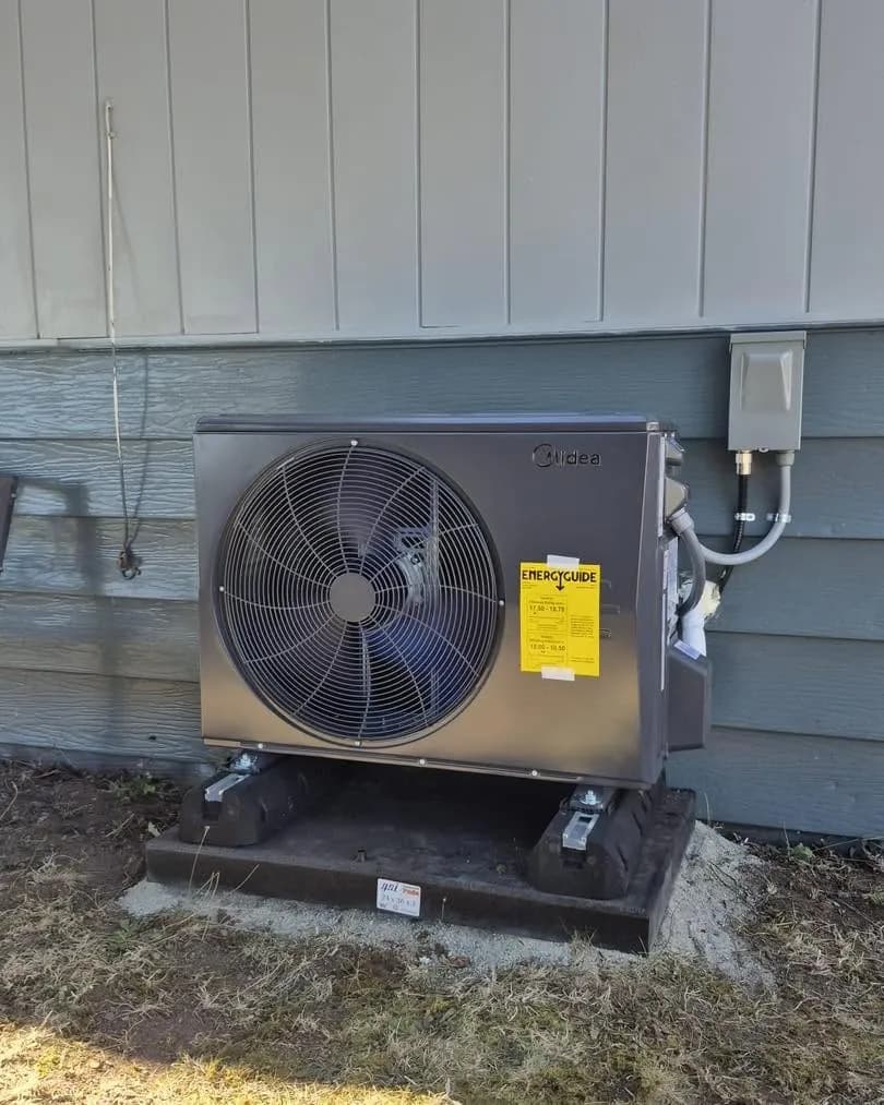 Heat pump against blue siding with a clean electrical disconnect