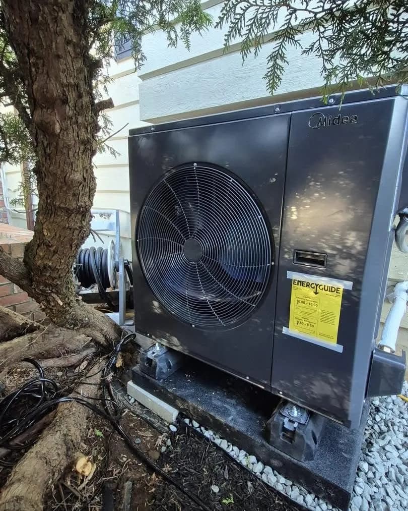 Heat pump beside a tree on a raised base